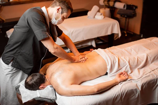 Masseur het doen van een diepe massage naar een mannelijke client — Stockfoto