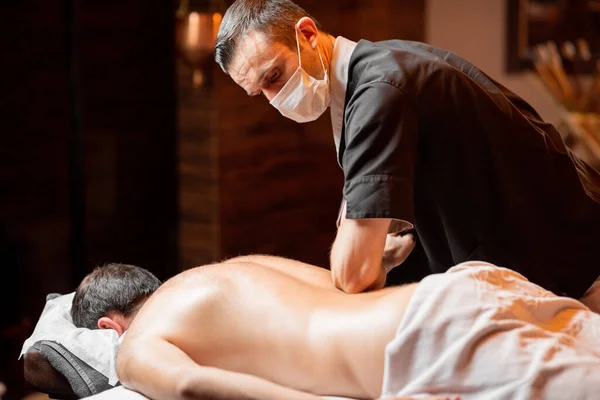 Masseur doing a deep massage to a male client — Stock Photo, Image