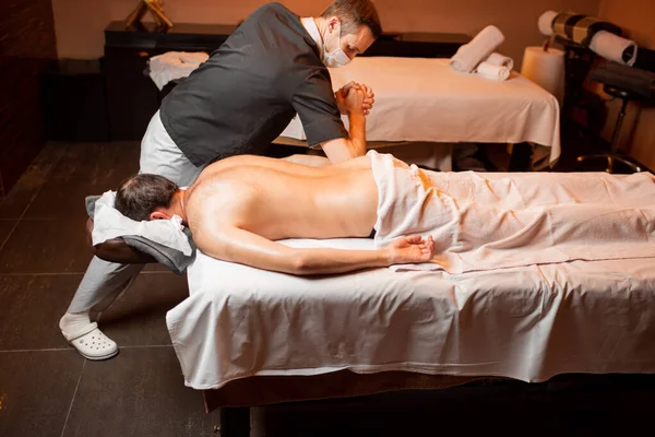 Masseur doing a deep massage to a male client — Stock Photo, Image