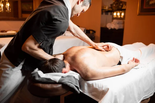 Masseur doing a deep massage to a male client — Stock Photo, Image