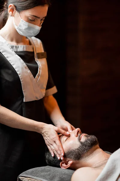 Female masseur doing facial massage to a male client — Stock Photo, Image