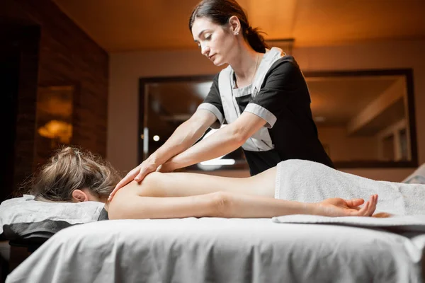 Masajista haciendo masaje de espalda a una clienta femenina —  Fotos de Stock