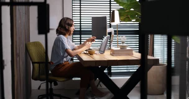 Femme travaille sur un ordinateur portable à la maison confortable bureau — Video