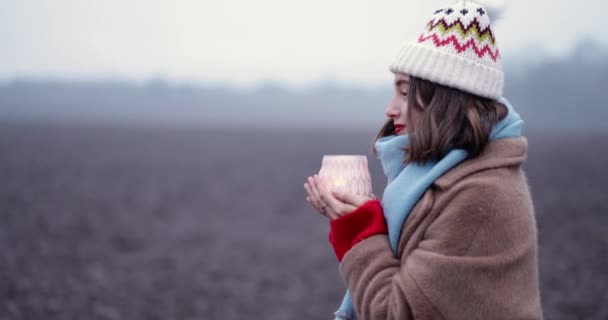 Donna in abiti invernali a lume di candela sul campo — Video Stock