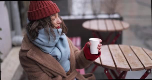 Femeia care bea băutură caldă la cafenea iarna — Videoclip de stoc
