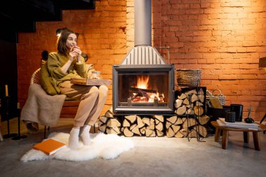 Evde şöminenin başında dinlenen bir kadın.