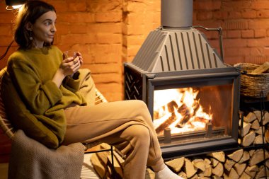 Evde şöminenin başında dinlenen bir kadın.