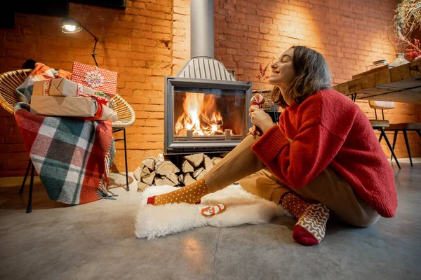 Femme avec des bonbons près de la cheminée pendant les vacances d'hiver — Photo