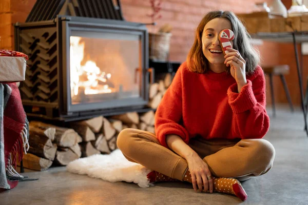 Woman with candy by the fireplace during a winter holidays — Stock Photo, Image