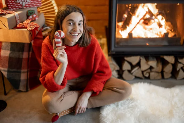 Femme avec des bonbons près de la cheminée pendant les vacances d'hiver — Photo