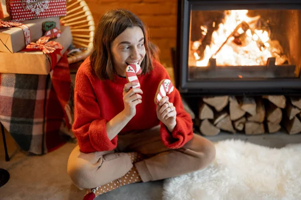 Femme avec des bonbons près de la cheminée pendant les vacances d'hiver — Photo