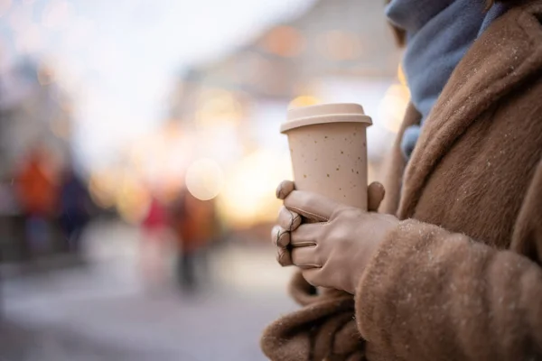 Woman holding a takeaway coffee on the Christmas market background — Stock Photo, Image