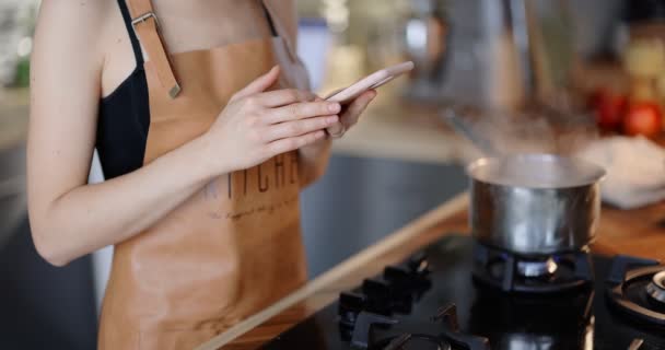 Donna che utilizza il telefono durante la cottura — Video Stock