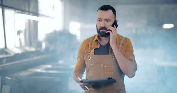 Gyári dolgozó táblagéppel és telefonnal a gyártásban — Stock videók