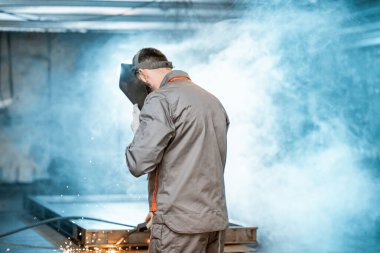 Kaynakçı atölyede metalle çalışıyor.