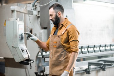 Fabrikada metal büken bir işçi.