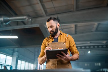 Fabrikada dijital tabletli metal endüstrisi işçisi.