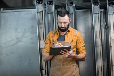 Fabrikada dijital tableti olan bir işçi.