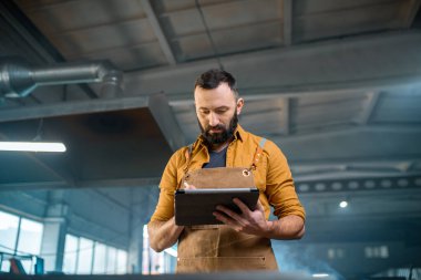 Fabrikada dijital tabletli metal endüstrisi işçisi.