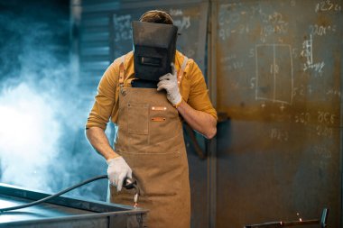 Kaynakçı atölyede metalle çalışıyor.