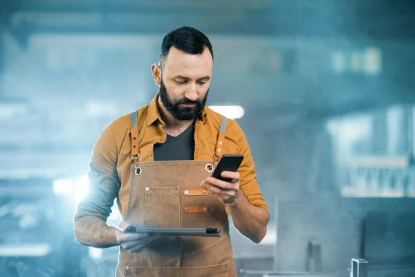 Fabrika işçisi, tablet ve telefonla imalat alanında çalışıyor. — Stok fotoğraf