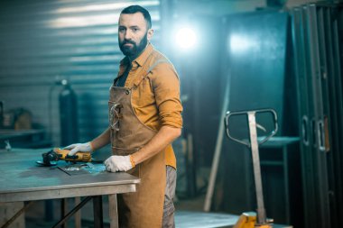 Adam atölyede metalle çalışıyor.