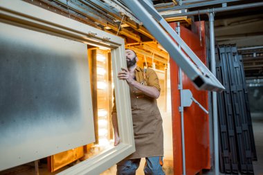 İşçi, boyanın kalitesini toz kaplama metal ürünleriyle kontrol ediyor