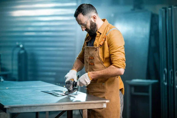 Человек, работающий с металлом в мастерской — стоковое фото