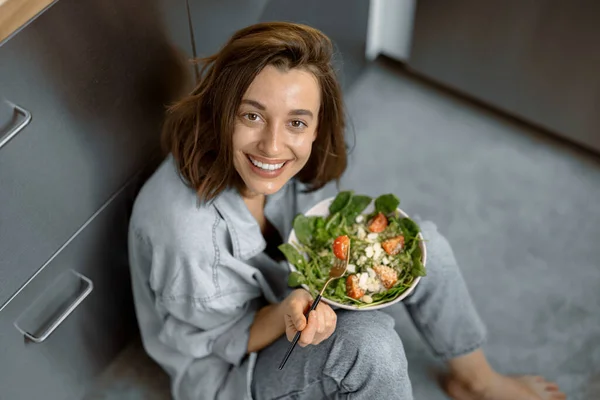 Kvinna med hälsosam sallad på köket — Stockfoto