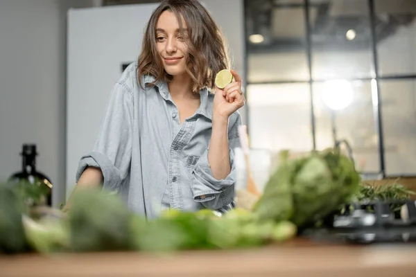 Mulher com ingredientes verdes na cozinha — Fotografia de Stock
