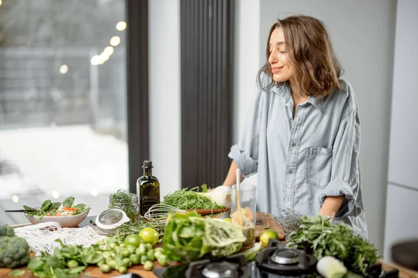 Mutfakta yeşil malzemeleri olan bir kadın. — Stok fotoğraf