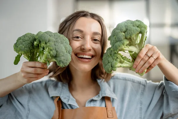 Kvinna med färsk broccoli på köket — Stockfoto