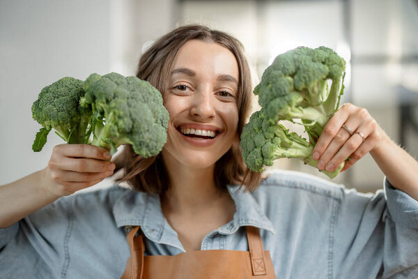 Woman with fresh broccoli on the kitchen
