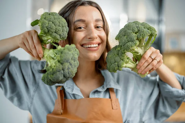 Kvinna med färsk broccoli på köket — Stockfoto