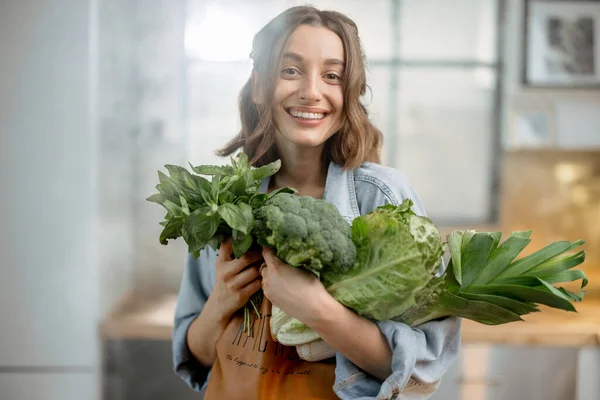 Γυναίκα με φρέσκα πράσινα λαχανικά στην κουζίνα — Φωτογραφία Αρχείου