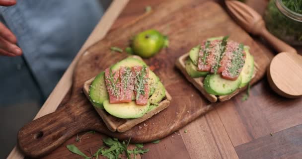 Vrouw die avocado toast eet in de keuken — Stockvideo