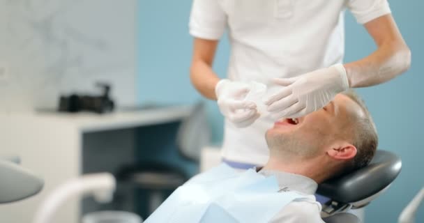 Dentista vistiendo oprimido para el paciente masculino, — Vídeo de stock