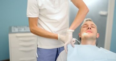 Erkek bir hastaya diş önlüğü takmak.