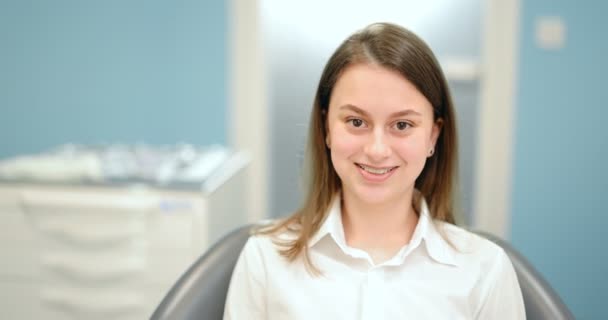 Portret wesołej dziewczyny w aparacie dentystycznym w gabinecie stomatologicznym — Wideo stockowe