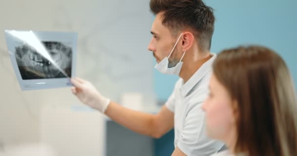 Dentista che mostra la radiografia di una mascella per un giovane paziente — Video Stock