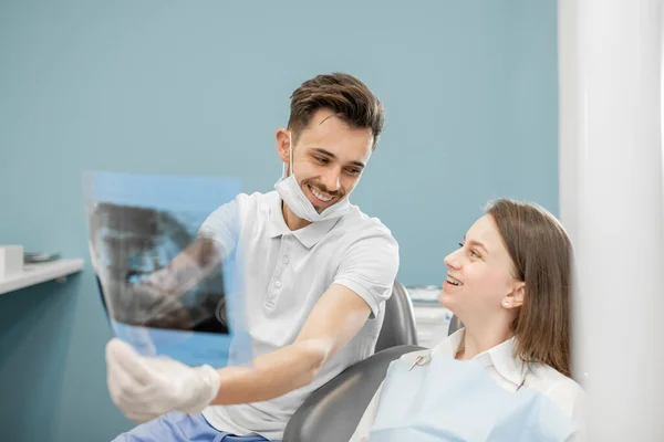 Дантист показывает рентген челюсти молодому пациенту — стоковое фото