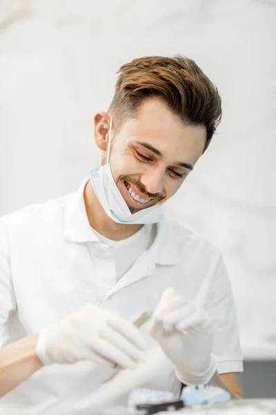 Técnico dentário trabalhando com um modelo de dentes e aparelhos dentários — Fotografia de Stock