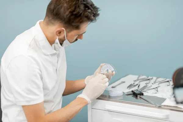 Técnico dentário trabalhando com um modelo de dentes e aparelhos dentários — Fotografia de Stock