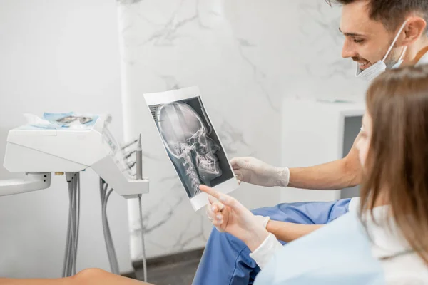 Dentista mostrando raio-X de um crânio para paciente jovem — Fotografia de Stock