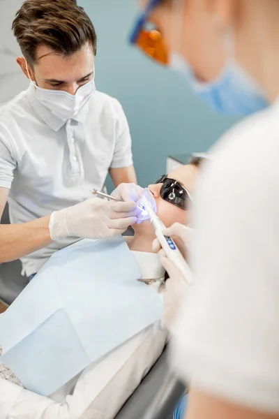 Homme dentiste et assistant utilisant la lumière de durcissement dentaire — Photo