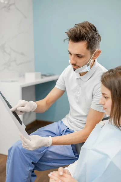 Dentista mostrando raio-X de um crânio para paciente jovem — Fotografia de Stock