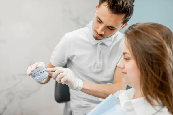 Dentiste montrant un prototype de mâchoire pour un jeune patient — Photo