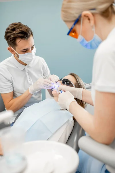 歯科治療用ライトを使用した男性歯科医とアシスタント — ストック写真
