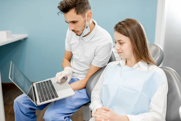 Dentista mostrando foto de dentes em um monitor para um paciente jovem — Fotografia de Stock