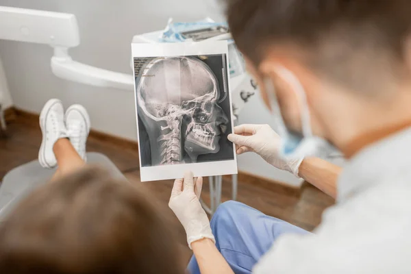 Tannlege som viser røntgen av en skalle for ung pasient – stockfoto
